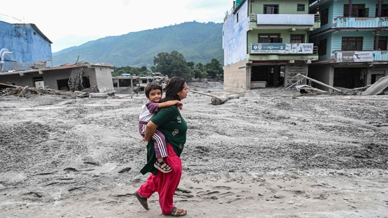 a-woman-carrying-her-child-walks-along-a-road-deluged-in-sludge-after-flash-floods-at-devighat-in-nepal-6a9244a41084e-4d307846bb6f996a45abbe6077a393ef1787977323.jpg